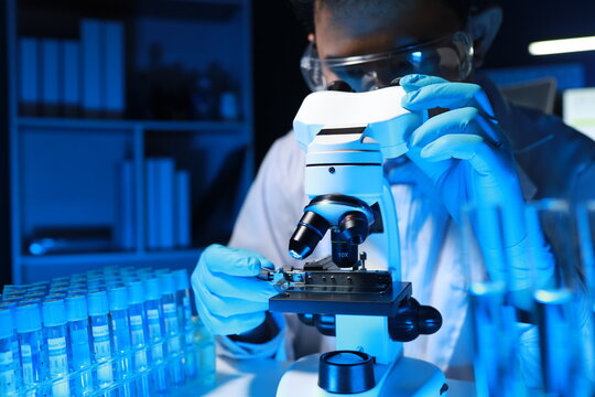 A talented scientist sits in his lab while using a microscope to look for microscopic organisms in a test sample, microscope It is used by researchers to find new medicines to treat people.