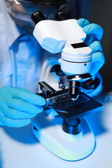 A talented scientist sits in his lab while using a microscope to look for microscopic organisms in...