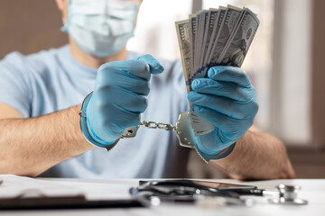 A doctor with dollar bank notes and handcuffs. concept of medical corruption, bribery, crime