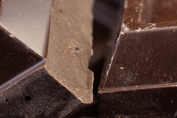 Broken chocolate. Chocolate pieces. Chocolate pieces on dark background.