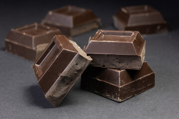 Broken chocolate. Chocolate pieces. Chocolate pieces on dark background.