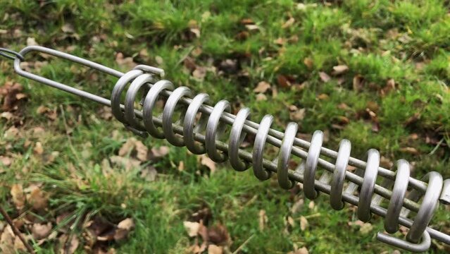 Electric fence with metal spring coil connection part, green meadow of a paddock or pasture in the countryside