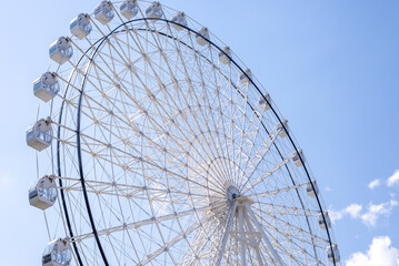 Ferris wheel in white color against summer blue sky