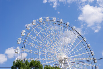 Ferris wheel in white color against summer blue sky