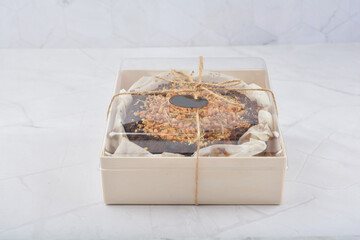 premium freshly baked dark cocoa chocolate brownie gold flower and earl grey peanut round birthday cake with walnut in wood bento box on white marble halal food sweet dessert menu for pastry cafe shop