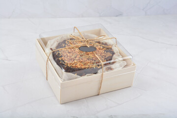 premium freshly baked dark cocoa chocolate brownie gold flower and earl grey peanut round birthday cake with walnut in wood bento box on white marble halal food sweet dessert menu for pastry cafe shop