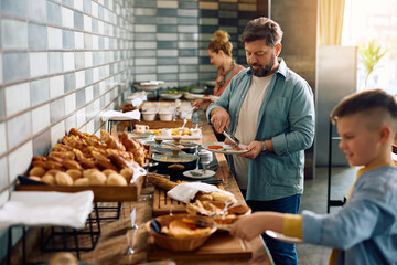 Mature man having breakfast while being with his family in hotel.