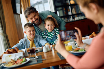 Happy family having fun while being photographed during  breakfast in hotel restaurant.