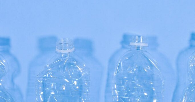 Close up video of plastic bottles isolated on blue background. Recycle waste management video concept. Plastic PET bottles. Eco video banner with copy space.