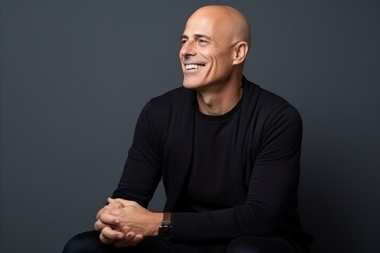 Portrait of a smiling middle-aged bald man in a black sweater