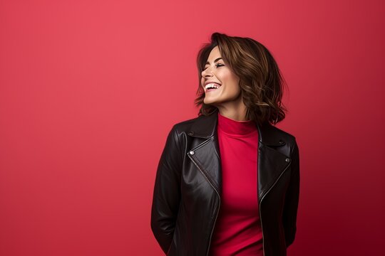 Portrait of a happy young woman in leather jacket on red background