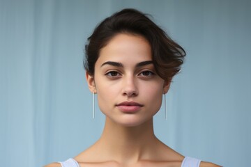 portrait of a beautiful young woman with earrings on blue background