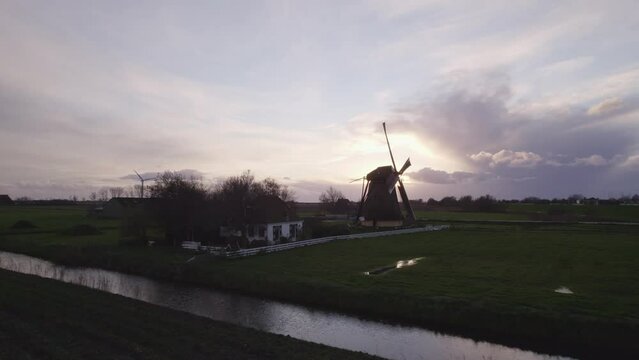 Aerial view of famous spinning Dutch windmill (Nijlannermolen) at sunset, Workum, Netherlands