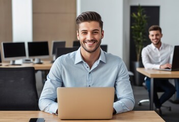 A man smiling while working on his laptop at the office. He appears relaxed and satisfied with his work.