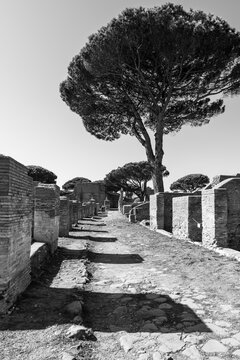 Black and white photo showing a street view of ancient roman town at archaeological park in Italy