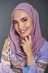 Beautiful female model wearing modern kebaya batik , an Asian traditional dress for Muslim woman isolated over grey background. Stylish Muslim female hijab fashion lifestyle portraiture concept.