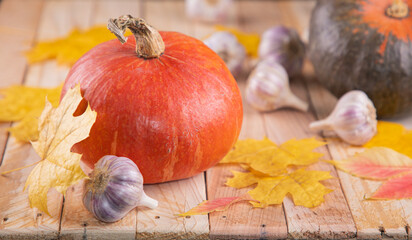 Pumpkins with garlic and leaves on wooden background. Objects for the Halloween holiday. Autumn...