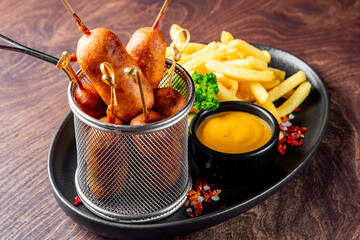 corn dog with mustard sauce and french fries on plate
