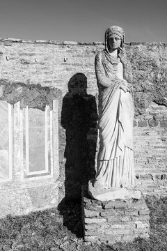 Black and white photo of ancient roman statue in ruins portraiting a woman wearing a veil