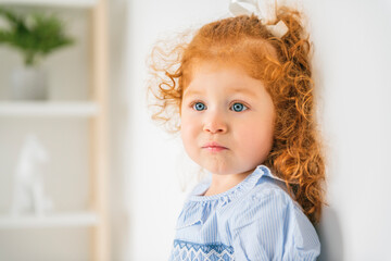 Little cute girl in a dress with redhead. The child is 2 years old.