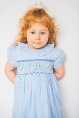 Little cute girl in a dress with redhead. The child is 2 years old.