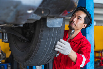 Japanese mechanic man checking car tire in tire shop 