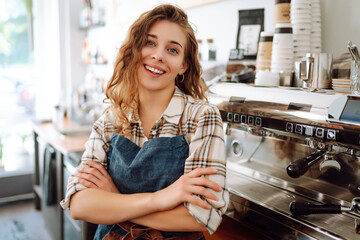 Portrait of a beautiful barista woman in an apron in a modern cafe bar. Business concept, food and drinks. - obrazy, fototapety, plakaty