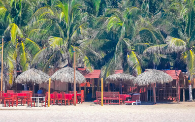 Palms parasols sun loungers beach waves Puerto Escondido Mexico.