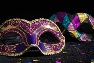 Masquerade mask with confetties on black background.