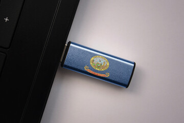 usb flash drive in notebook computer with the national flag of idaho state on gray background.