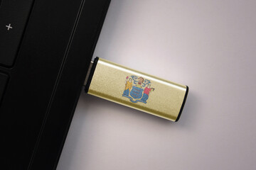 usb flash drive in notebook computer with the national flag of new jersey state on gray background.