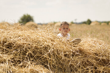 Naklejka na ściany i meble The boy lies on the hay and looks into the frame