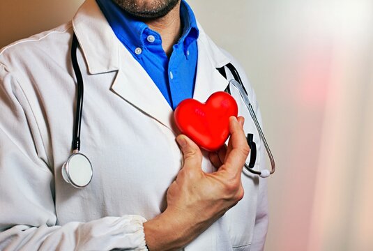 Man doctor is pictured holding a red heart. This image can be used to convey love, care, or support. It is suitable for various projects and designs.