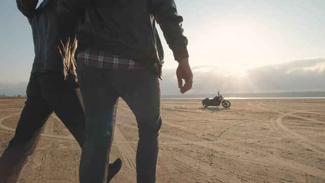 Guy with a girl on a motorcycle in the desert. Couple riding on vintage motorcycle and having a good time at sunset on a dry salt lake. Slow motion shot