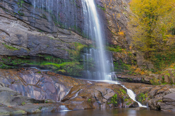 The idea of being in nature and the waterfall flowing through the trees decorated with autumn colors the rocks calmness peace and happiness