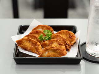 Gyoza in a black plate on a table in restaurant