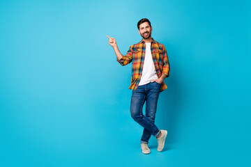 Full size photo of handsome positive man dressed plaid shirt jeans indicating at benefit empty...