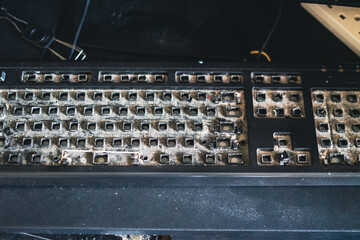 Dirty Qwerty keyboard full of dusts and debris on the table. Cleaning the computer.