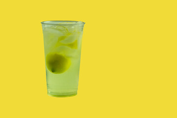 Fresh Squeezed Lemonade with lemons and ice in a clear plastic cup on yellow background