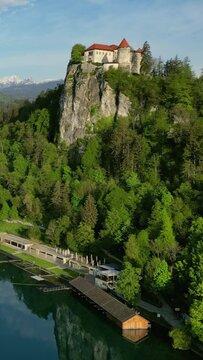 Aerial view of Bled lake with castle on the rock in morning light, Slovenia. Vertical video