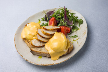 Eggs benedict with cheese and salad on a plate
