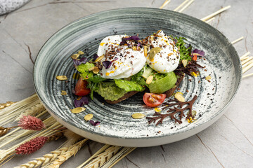 Poached egg with avocado, cherry tomatoes and arugula salad