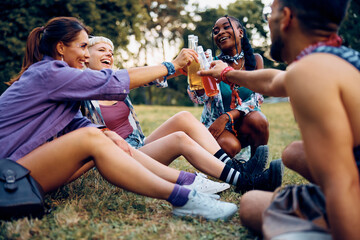 Happy group of festival goers toasting in park while waiting for music concert to begin. - obrazy, fototapety, plakaty