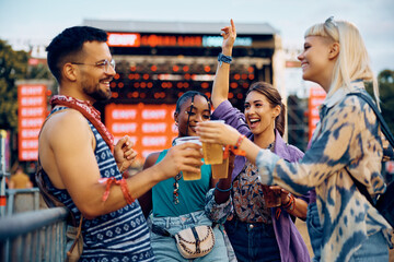 Multiracial group of cheerful people toasting with beer during summer music festival.
