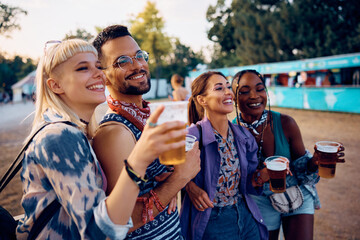 Happy friends attending live performance during summer music festival.