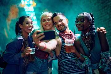 Happy festival goers having fun while taking selfie at night.
