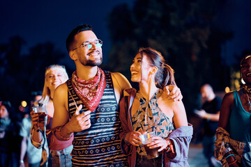 Young happy couple attending open air music concert at night.