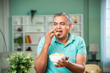 Indian mid age man eating potato chips