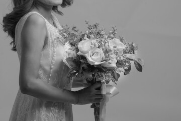 A bride in a white dress holds a bouquet of flowers in her hand.