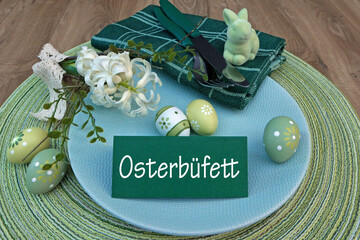 Gedeckter Ostertisch mit Osterdekoration und eine Tischkarte mit der Beschriftung Osterbüfett. - obrazy, fototapety, plakaty